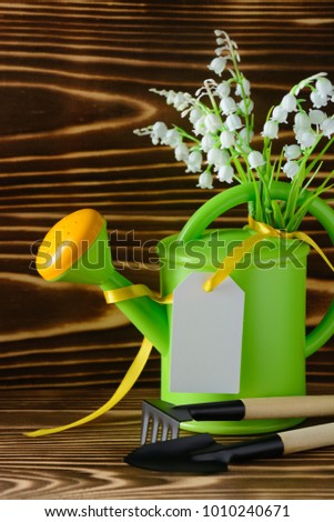 Garden watering can with label and tools for gardening on wooden table