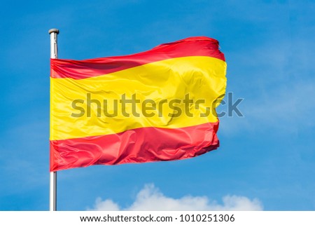 Closeup of single spanish flag waving in the wind in front of blue sky