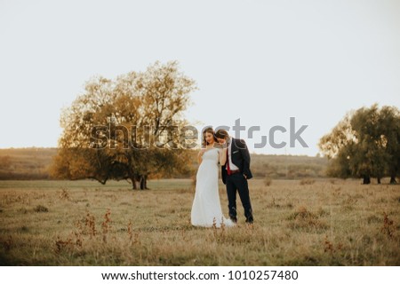 young wedding couple - freshly wed groom and bride posing outdoors on their wedding day