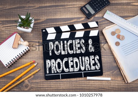 Policies and Procedures. movie clapper on a wooden desk