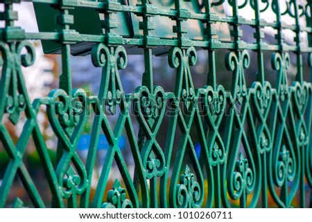 Abstract macro shot of green metal bridge railing in city centre. Beautiful heart shaped ornament decorations. Concept of love