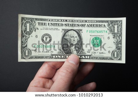 One dollar close-up in hand on a black background.