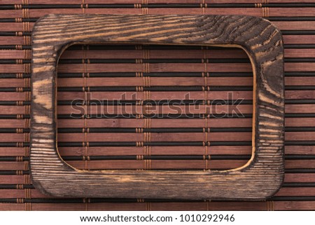 Beautiful one-piece dark wooden frame, lies on bamboo mat. Natural patterns, texture