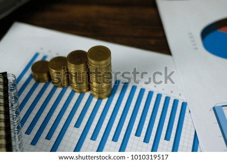 Step of coins stacks with notebook laptop computer and financial graph on white paper on working table, business planning vision and finance analysis concept idea. and copy space for add text.