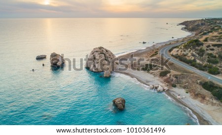 Aerial Bird's eye view of Petra tou Romiou, aka Aphrodite's rock a famous tourist travel destination landmark in Paphos, Cyprus. The sea bay of goddess Afroditi birthplace at sunset from above.  Royalty-Free Stock Photo #1010361496