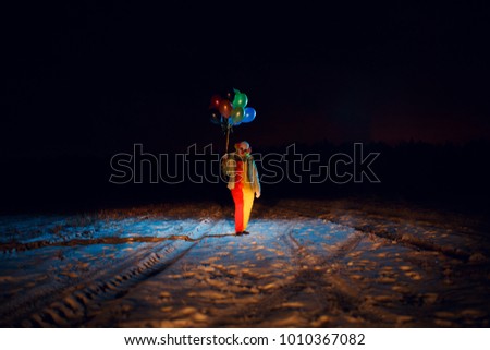 Full-length clown photo with colorful balloons at night