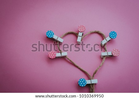 Pastel color wooden clothespin on rope heart shape on pink background.Valentine's Day concept.