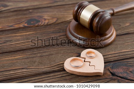 Wedding rings on the figure of a broken heart from a tree, hammer of a judge on a wooden background. Divorce divorce proceedings Royalty-Free Stock Photo #1010429098