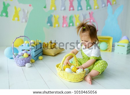 Cute little girl in a light green jumpsuit plays with Easter ducklings in the Easter interior, easter concept
