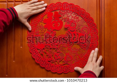 man sticking a Chinese New Year of the Dog 2018 to a door the Chinese means fortune