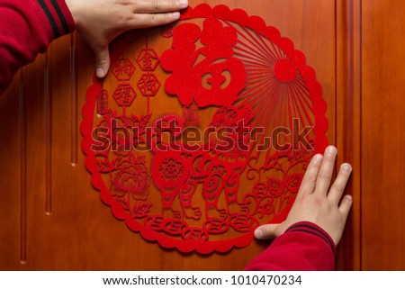 man sticking a Chinese New Year of the Dog 2018 to a door the Chinese means fortune and the Dog brings happy