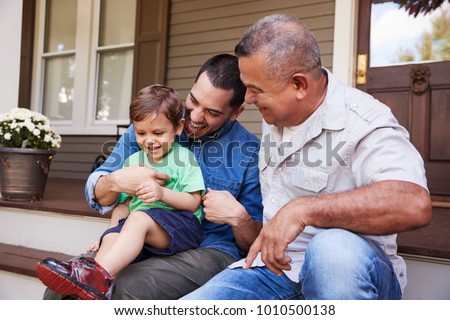 Male Multi Generation Family Sitting On Steps in Front Of House Royalty-Free Stock Photo #1010500138