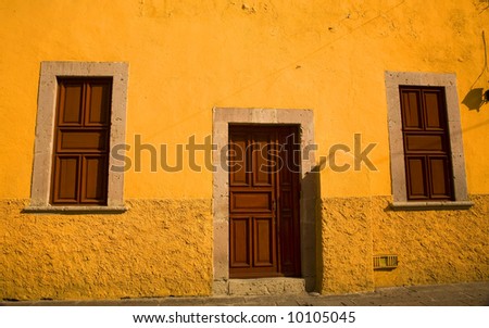 Bright Yellow Adobe House with brown doors Morelia Mexico Resubmit--In response to comments from reviewer have further processed image to reduce noise and sharpen focus.