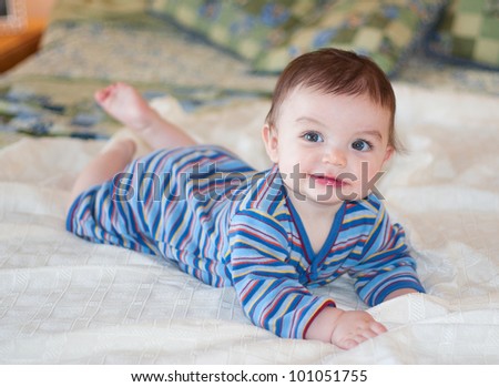 Baby lying on bed posing for picture wearing blue striped outfit