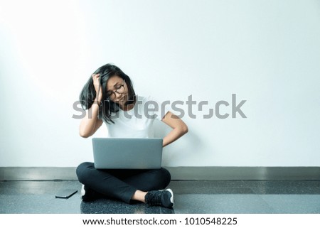 beauty girl student sitting on floor with white wall background and stressful jobs at with using laptop computer study.
