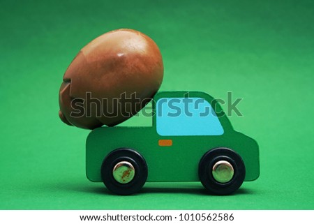 one alone chocolate Easter egg . holiday concept idea with egg on green toy car on wooden table isolated on green background. empty copy space for inscription or objects. springtime season