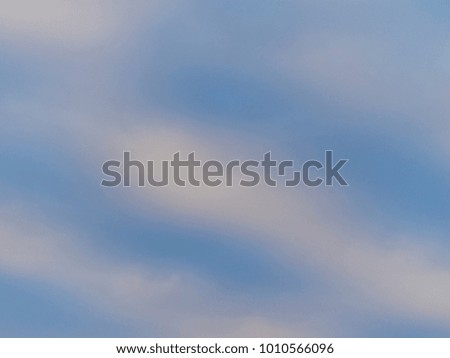 Abstract background of a partly cloudy blue sky with motion blur in the clouds.