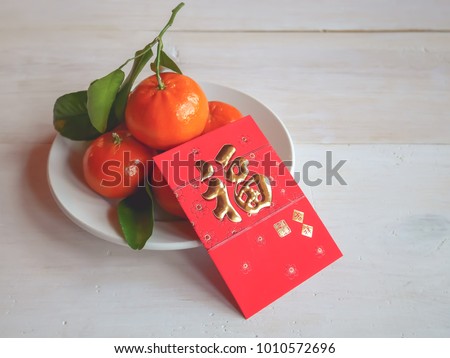 Selective focus image of red envelope or gratuity in new year chinese called Angpao with fresh oranges and green leaf on white table background / Selective focus and space for message