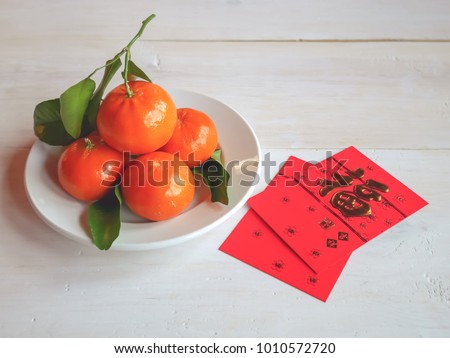 Selective focus image of red envelope or gratuity in new year chinese called Angpao with fresh oranges and green leaf on white table background / Selective focus and space for message