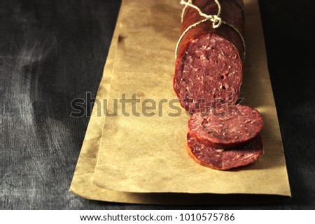 Sausage made of venison on a dark background. Dietary deer meat, pepper, salt, without preservatives. 