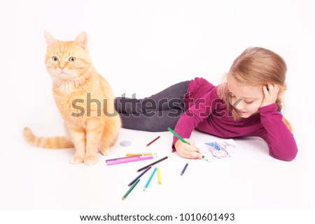 Little cute girl with colored pencils and red cat lying on the floor on a white background