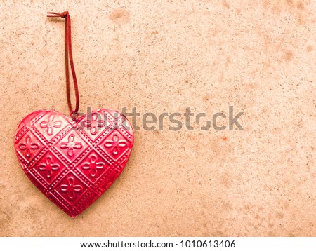 Close-up red metal heart on a background of light pink yellow grey stone Valentines day anniversary mothers day birthday couple wedding card womans day background with copy space