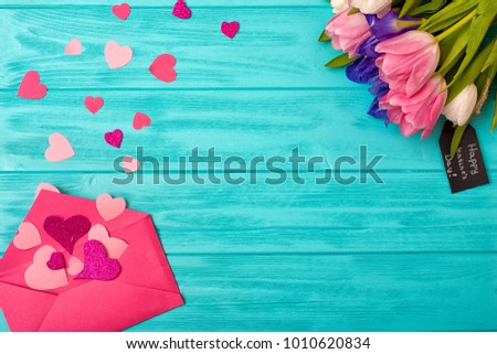  Valentines Day background with bouquet of tulips a gift and open envelope in which there are a lot of pink hearts.Happy moments.