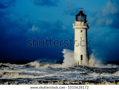 A resilient lighthouse standing up to crashing waves during a storm Royalty-Free Stock Photo #1010628172