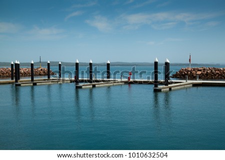 Empty boat marina with view of ocean, sunny day with blue skies and light clouds. Location is Anchorage Marina, Port Stephens Australia. Royalty-Free Stock Photo #1010632504