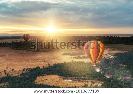 Beautiful aerial view of colorful hot air balloons floating over the Masai Mara National Reserve at golden sunrise Royalty-Free Stock Photo #1010697139