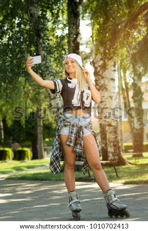 Teenage girl in roller skates taking a selfie on smart phone