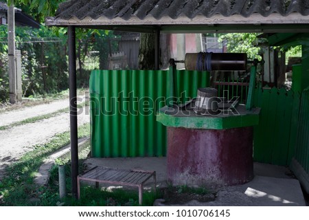 Old well with water in village, green color.