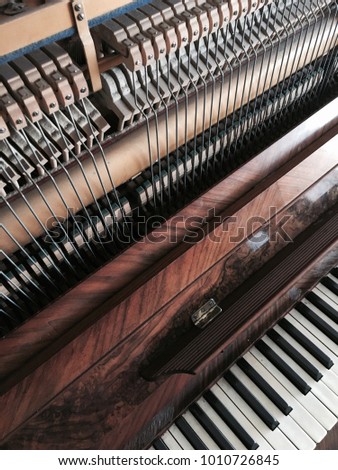 Detail of a wall piano, where you can see the keyboard next to the internal mechanism of musical notes seen from above