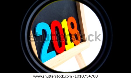 Closeup of wooden black board with colourful word 2018 on white background. Selective focus and crop fragment. 