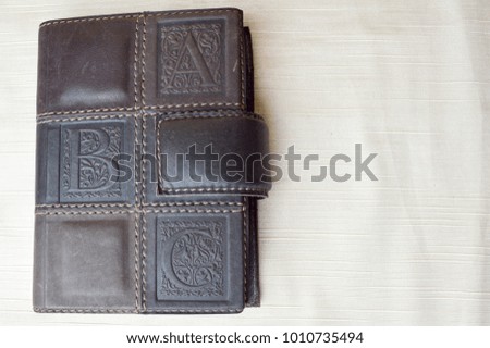 A brown, old, leather-covered notebook on a beige background.
