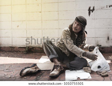 Asian vagrant is siting on the cardboard on the sidewalk.
  Royalty-Free Stock Photo #1010755501