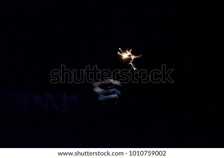 happy holidays.Vintage flim grain Style. Abstract blur background,woman hand holding a burning sparkler light with purple sky background.closeup in female hand in dark.