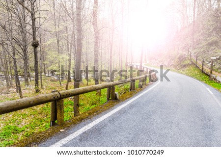 Morning mist over the asphalt road in the Italian Alps in Piedmont. View of the mountain valley with highway at sunrise