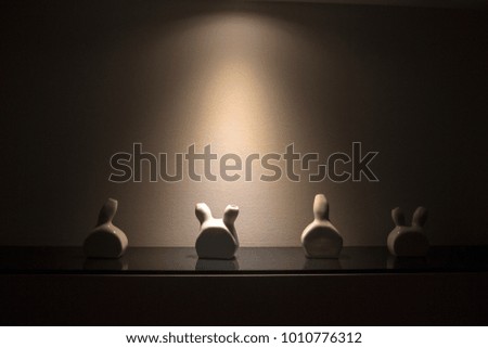 Small white porcelain vases on a shelf, with a spot light over them.