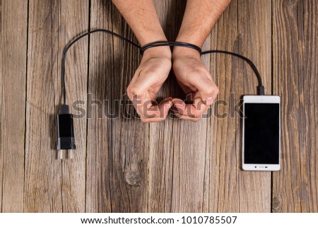 human hands are associated with charging of the phone as a symbol of dependence on technology and workaholism.