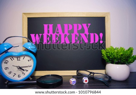 HAPPY WEEKEND! text written on blackboard with blue clock , magnifying lens and green plant.