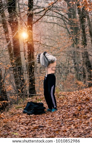 Man doing boxing exercises in forest.Sportsman with muscular body on white sky. Fitness and sport. Athlete training outdoors. Healthy lifestyle concept.