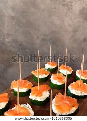 smoked salmon canapes on grey background. appetizer canapes of cucumber with smoked salmon for holiday. 