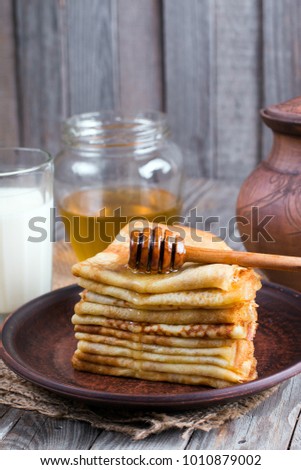 Stack of classic Russian thin pancakes (bliny) or crepes with honey on a plate. Traditional for the Russian pancake week (Maslenitsa).