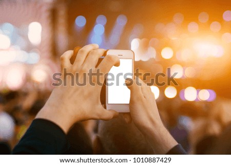 Hand with a smartphone records live music festival, Taking photo of concert stage, live concert on summer outdoor fest. White screen