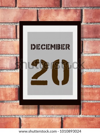 December 20th. 20 December calendar on the wood photo frame with brown brick background. New year at work concept. Winter time.