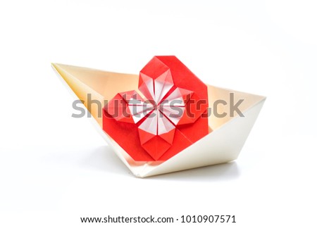a big red origami heart in a paper yellow boat on a white background