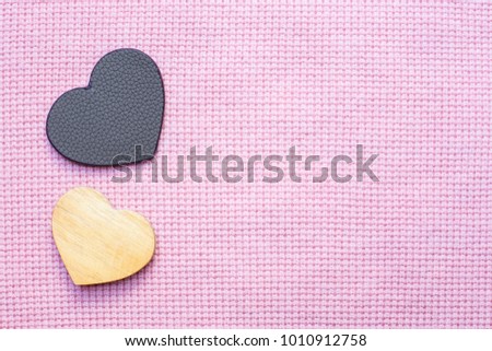 leather and wooden heart-shaped on pink fabric background