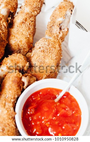 Traditional American homemade deep-fried breaded chicken drumsticks served with hot chili sriracha ketchup dipping sauce on game Sunday for Football Super Bowl party with family and friends