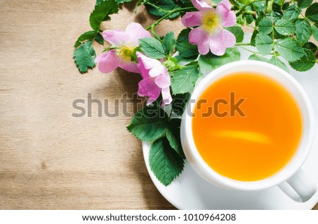 White cup of morning tea with lemon and delicate flowers on wooden rustic table. Cozy breakfast copy space